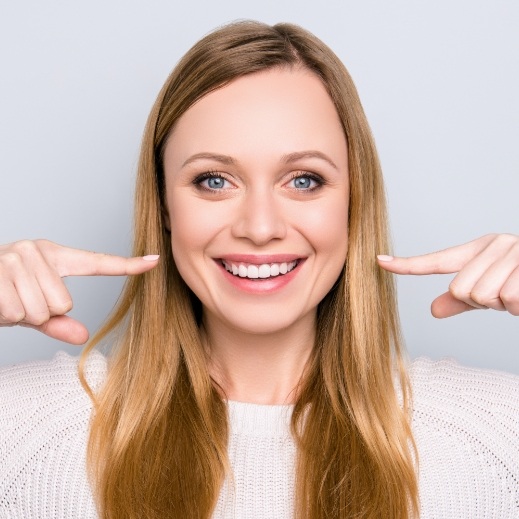 Woman pointing to her smile after dental bonding